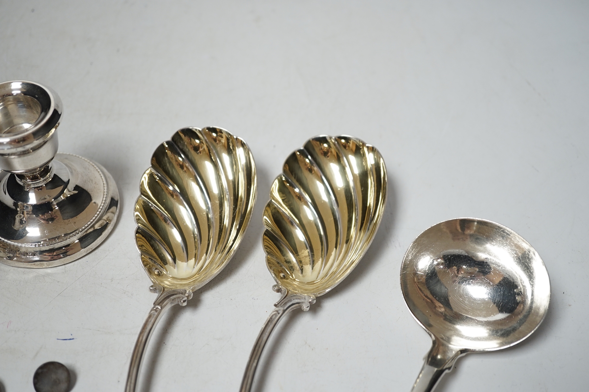 A pair of late Victorian silver serving spoons, with wavy foliate handles, Sheffield, 1897, 22.7cm, three other silver spoons and a pair of silver mounted dwarf candlesticks.